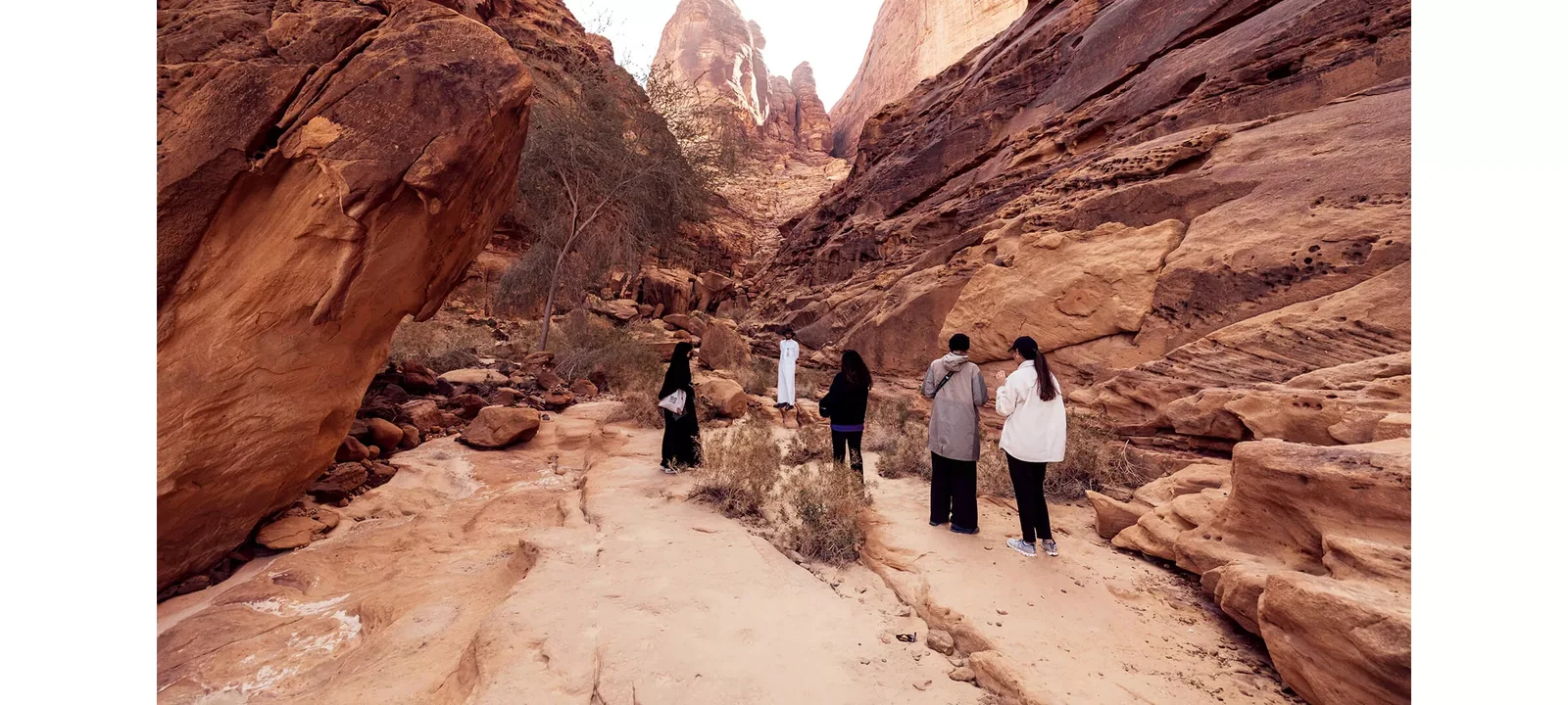 Visitors walking through the sandstone canyon at Jabal Ikmah