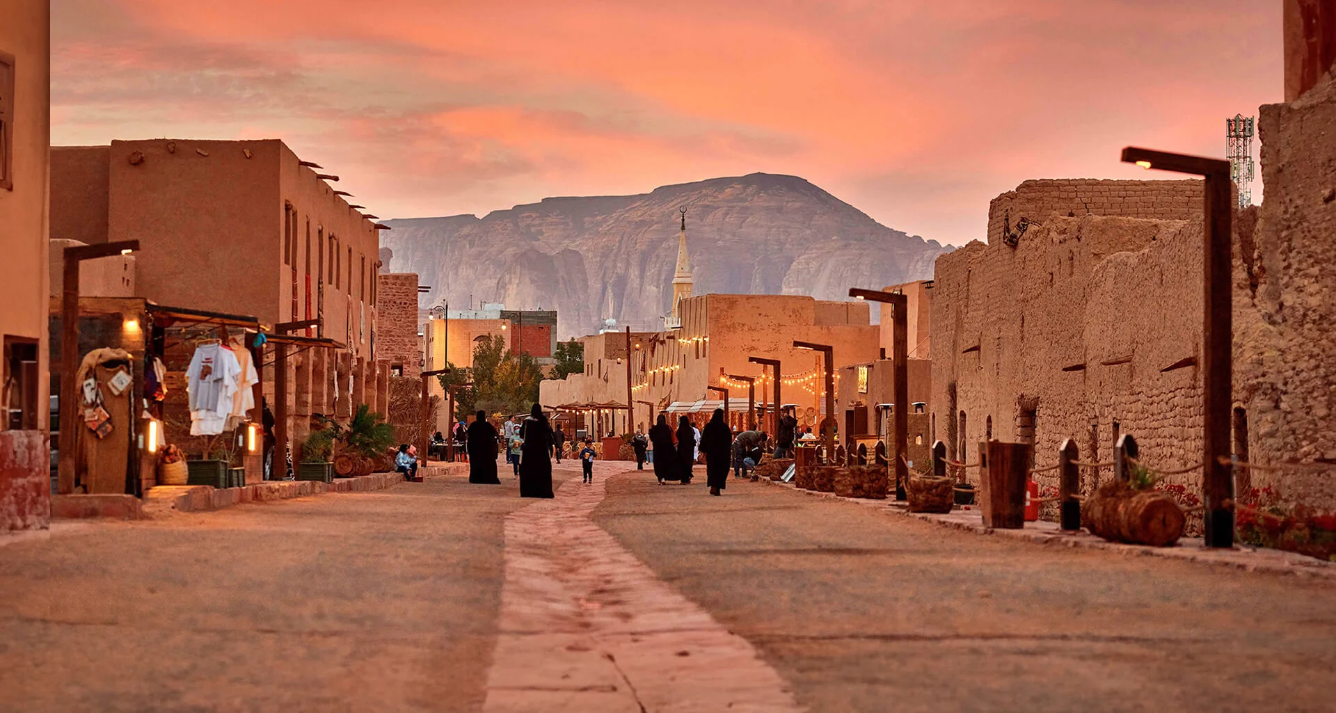 Visitors walking through AlUla Old Town at sunset